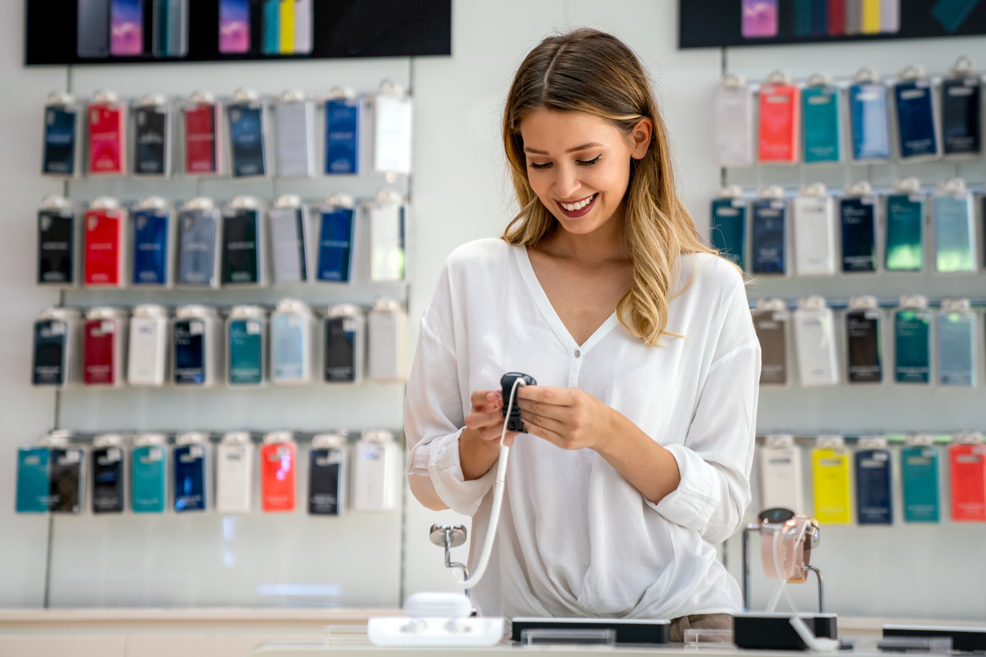 Smiling woman testing a smartwatch in-store, confident in her purchase thanks to the flexible UnitedTech return policy for wearable tech.

