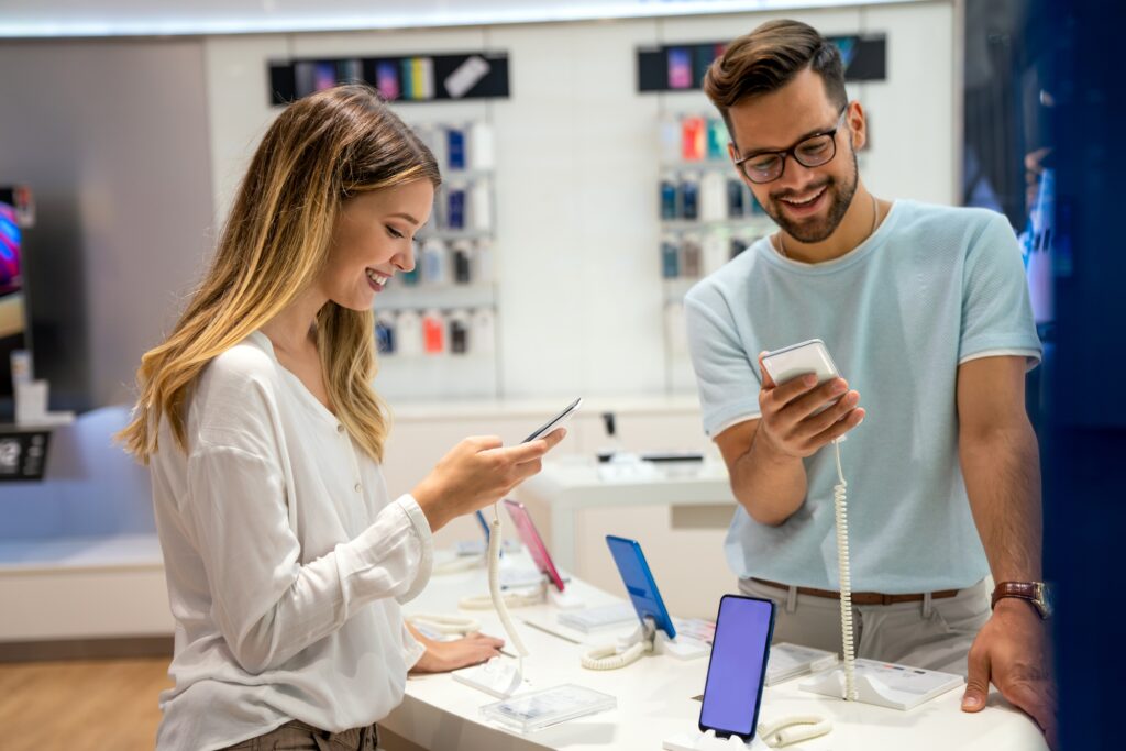 Two customers exploring smartphones at a modern tech store—perfect visual for a smart devices blog Florida highlighting the latest trends in consumer technology and mobile innovation.