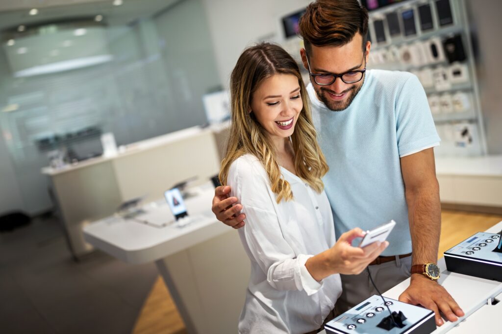 A cheerful couple exploring new devices in a high-tech retail store—ideal for illustrating consumer trends and shopping behavior in electronics news Florida coverage.